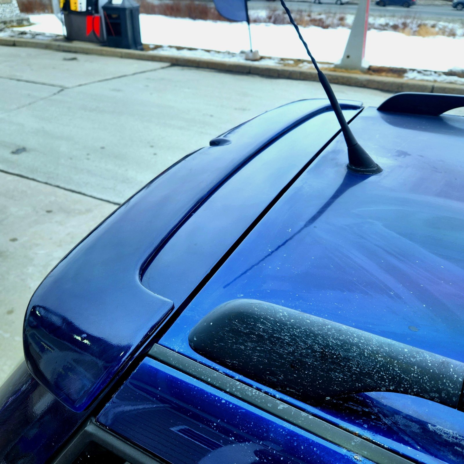 Close-up of an OEM-style rear hatch spoiler installed on a blue Volkswagen MK4 wagon