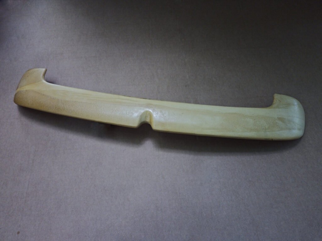 Unfinished rear hatch spoiler for a Volkswagen MK4 wagon photographed on cardboard
