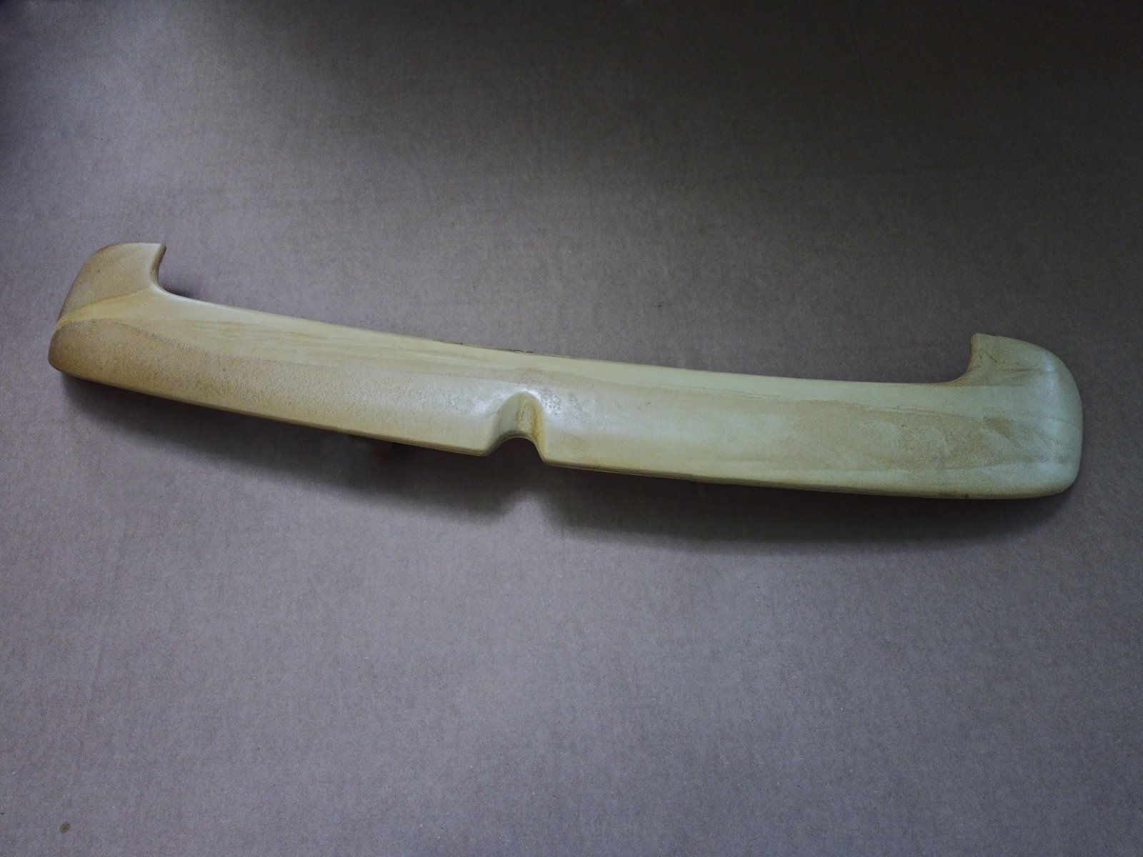 Unfinished rear hatch spoiler for a Volkswagen MK4 wagon photographed on cardboard